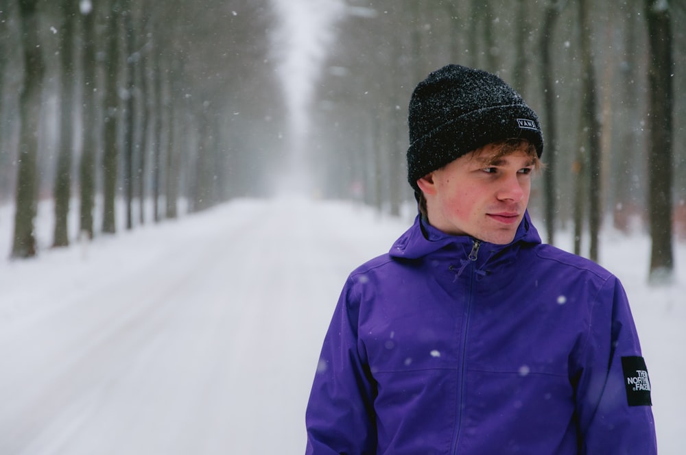 woman in blue jacket and black knit cap standing on snow covered ground during daytime