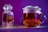 A glass jar containing saffron sits next to a transparent teapot filled with saffron tea. The vibrant orange hues of the saffron contrast with the bright purple background, creating a visually striking composition.