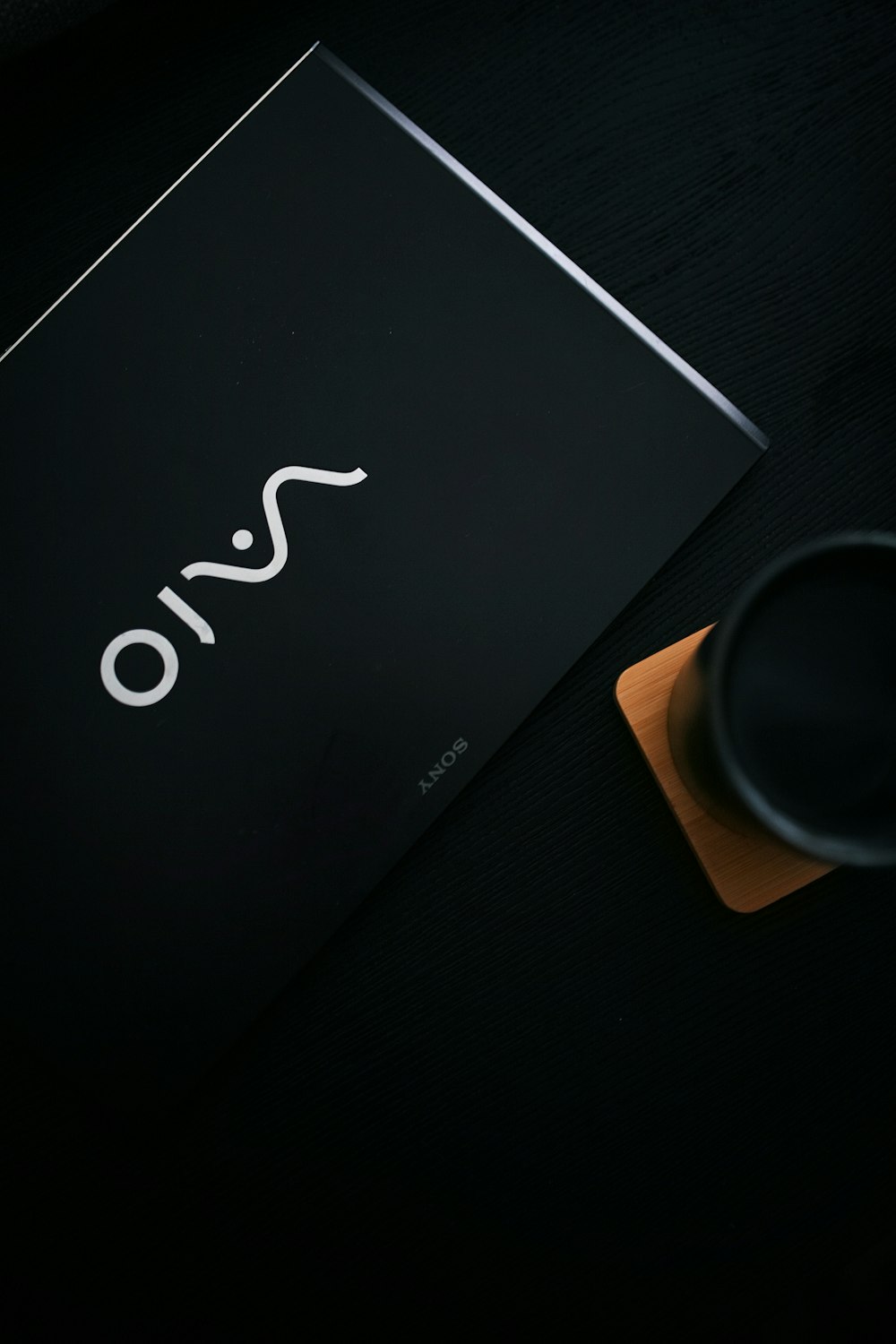 black sony vaio laptop beside black ceramic mug on brown wooden table