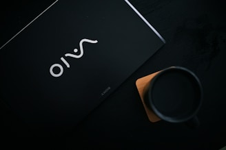 Elegant black acrylic coaster with a custom logo etched by laser, resting on a white surface