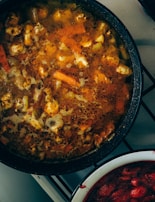 A slow cooker bubbling with a hearty stew, surrounded by fresh herbs and spices.