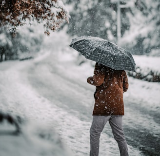 person in brown jacket and white pants holding umbrella