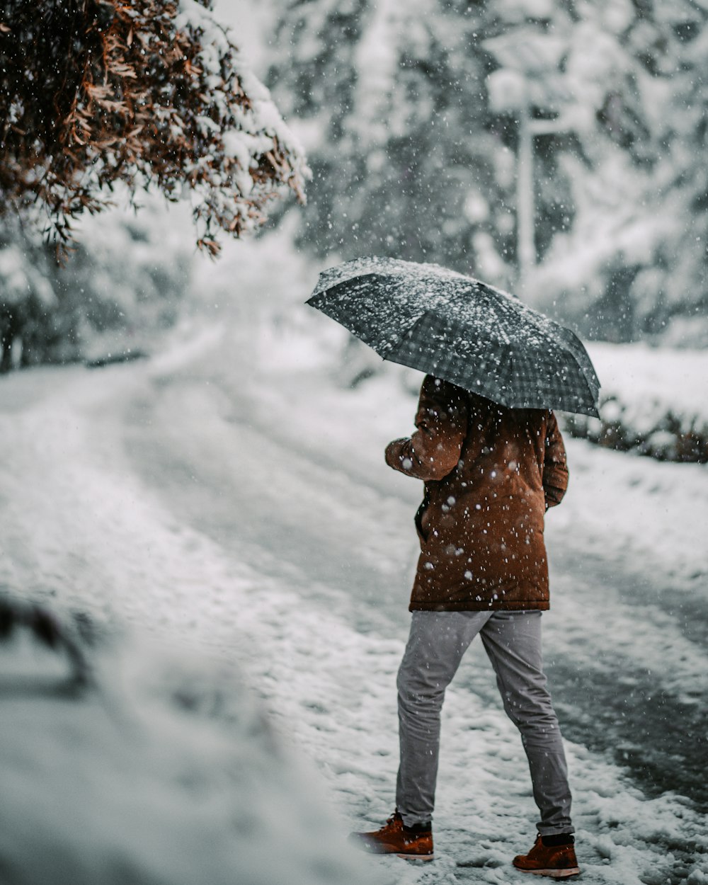 person in brown jacket and white pants holding umbrella