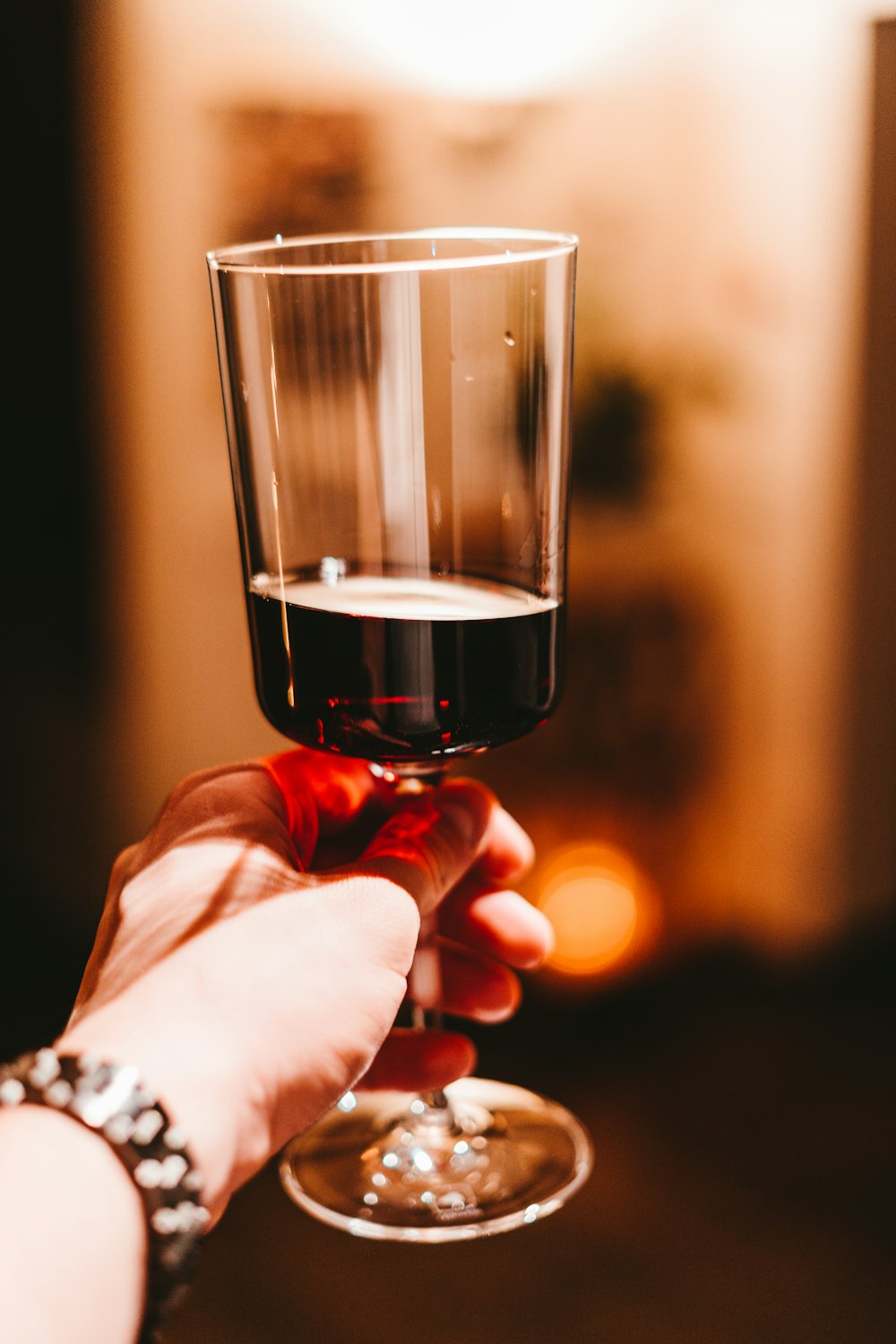 personne tenant un verre de vin transparent avec du vin rouge