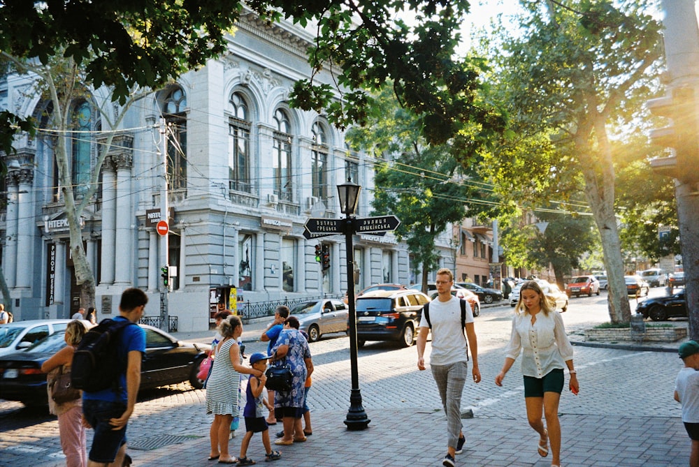 people walking on sidewalk near white concrete building during daytime