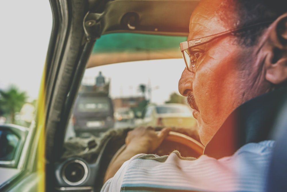 man in white dress shirt driving car during daytime