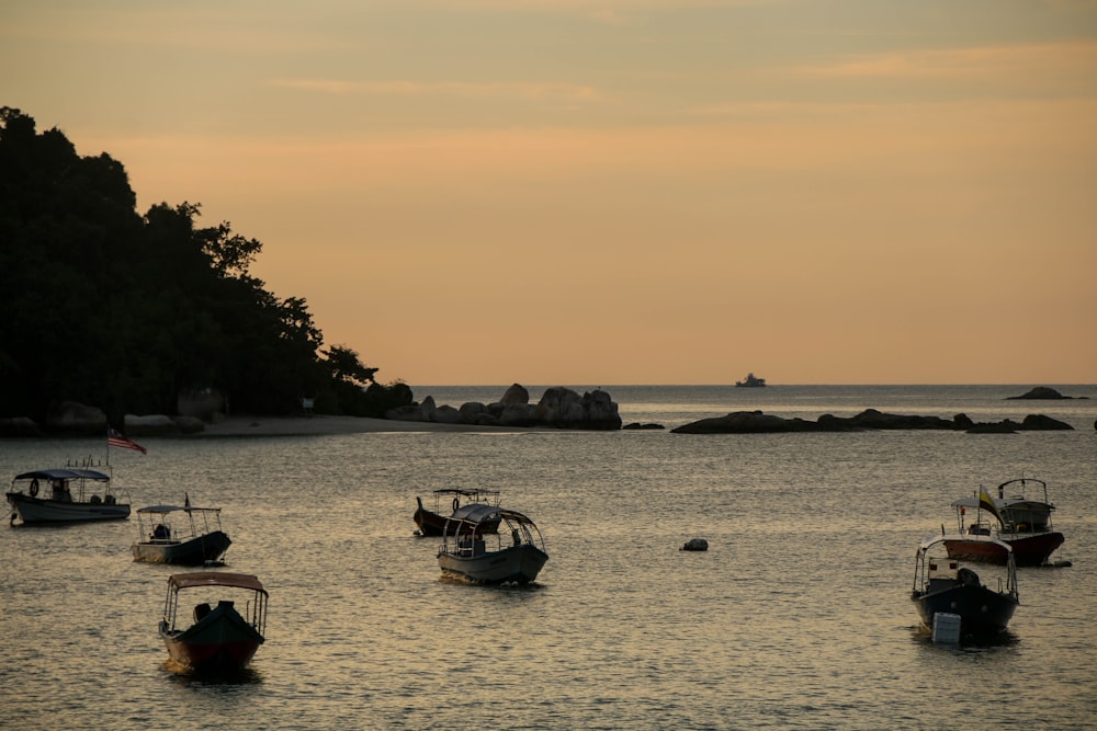 silhouette of people riding on boat on sea during sunset