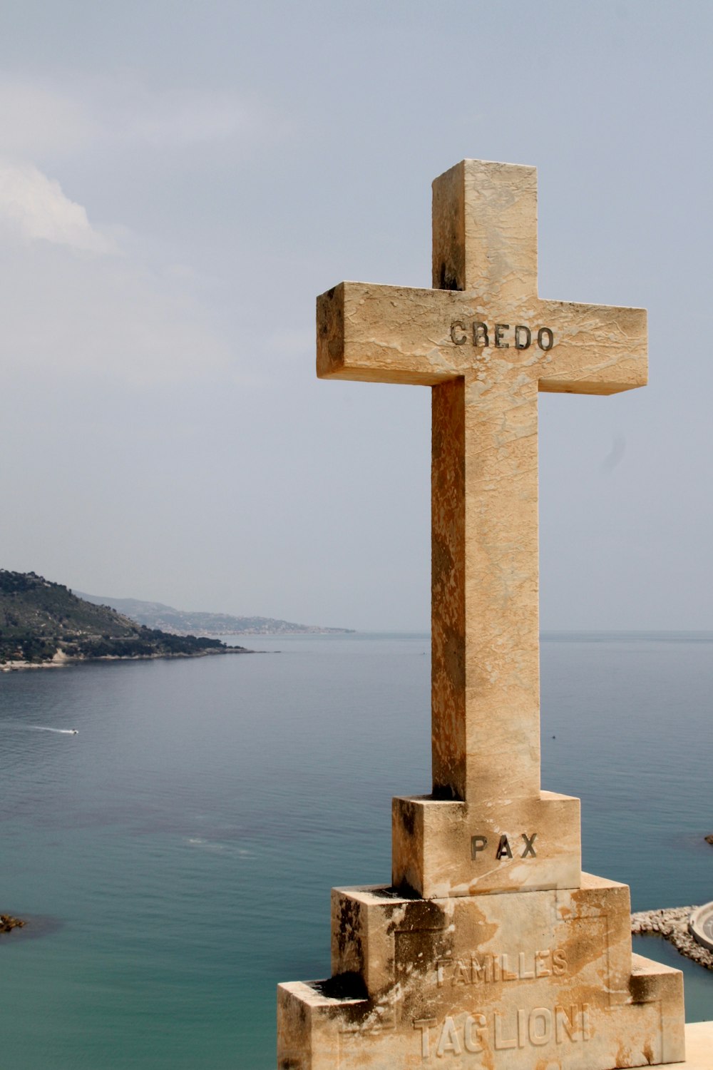 brown cross on brown wooden post near body of water during daytime