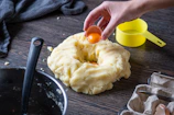 person holding orange plastic lid with white cream