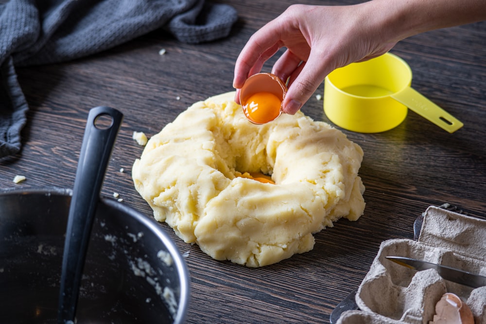 persona sosteniendo tapa de plástico naranja con crema blanca