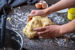 person holding bread on brown wooden table