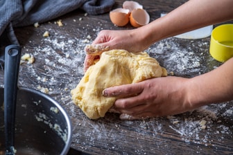 person holding bread on brown wooden table