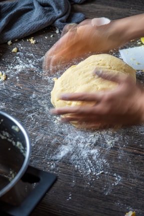 Baking class in session with participants kneading dough on floured wooden counters.