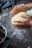 Close-up of hands kneading dough on a floured wooden board in a sunlit kitchen.