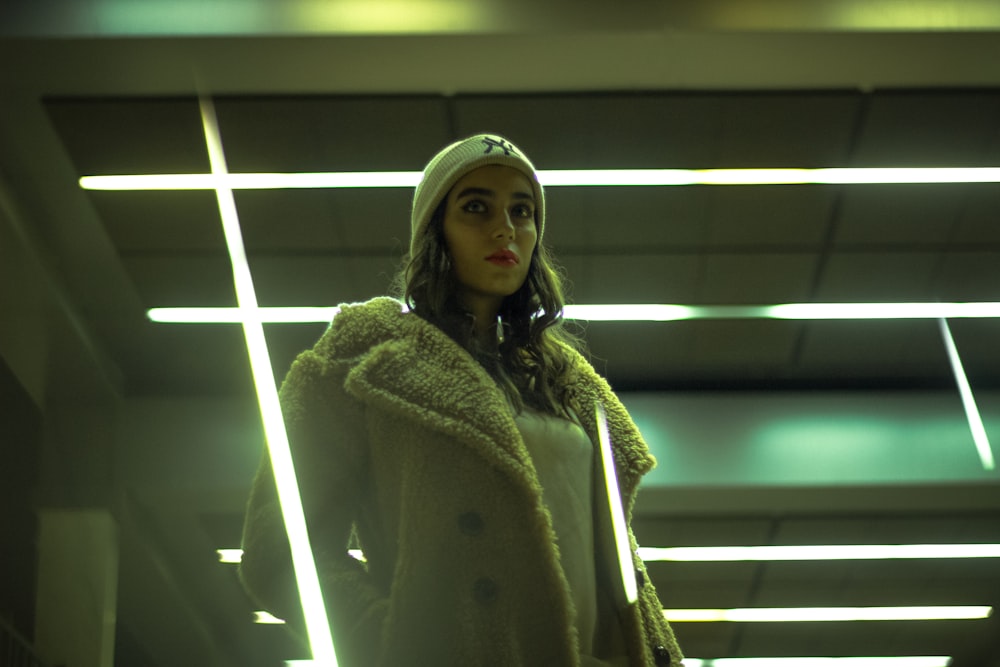 woman in white fur coat standing near window