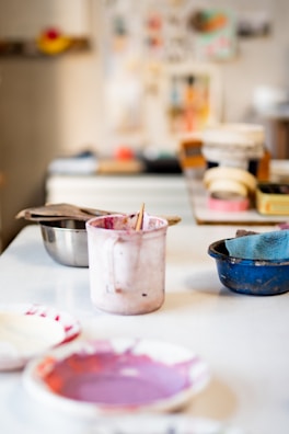 A behind-the-scenes photo of the artist’s workspace with brushes and canvases.