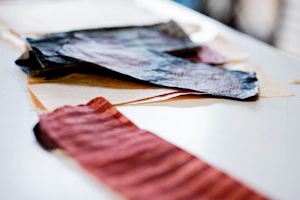 A variety of textured fabrics and vintage magazine clippings spread out on a table