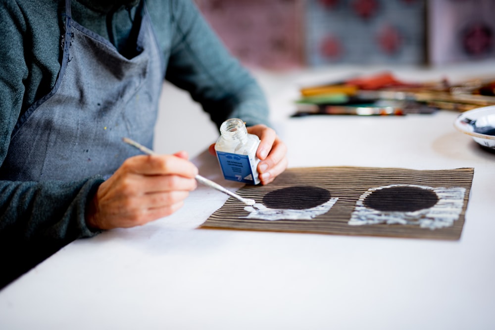 Persona con camisa gris de manga larga sosteniendo una taza de cerámica blanca y azul