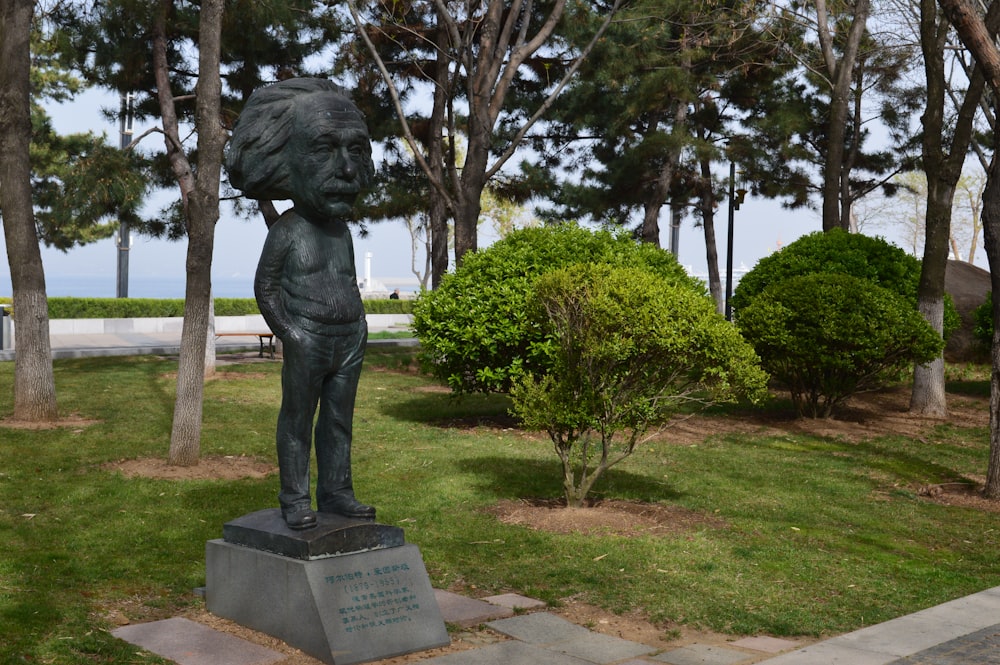 man statue near green trees during daytime