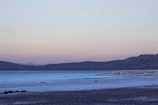 A serene lakeside view at sunrise with soft pastel skies and gentle ripples on the water