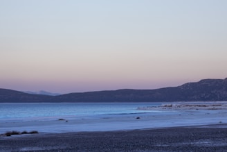 A serene Irish lakeside at dawn with soft blue and green hues reflecting on the water.