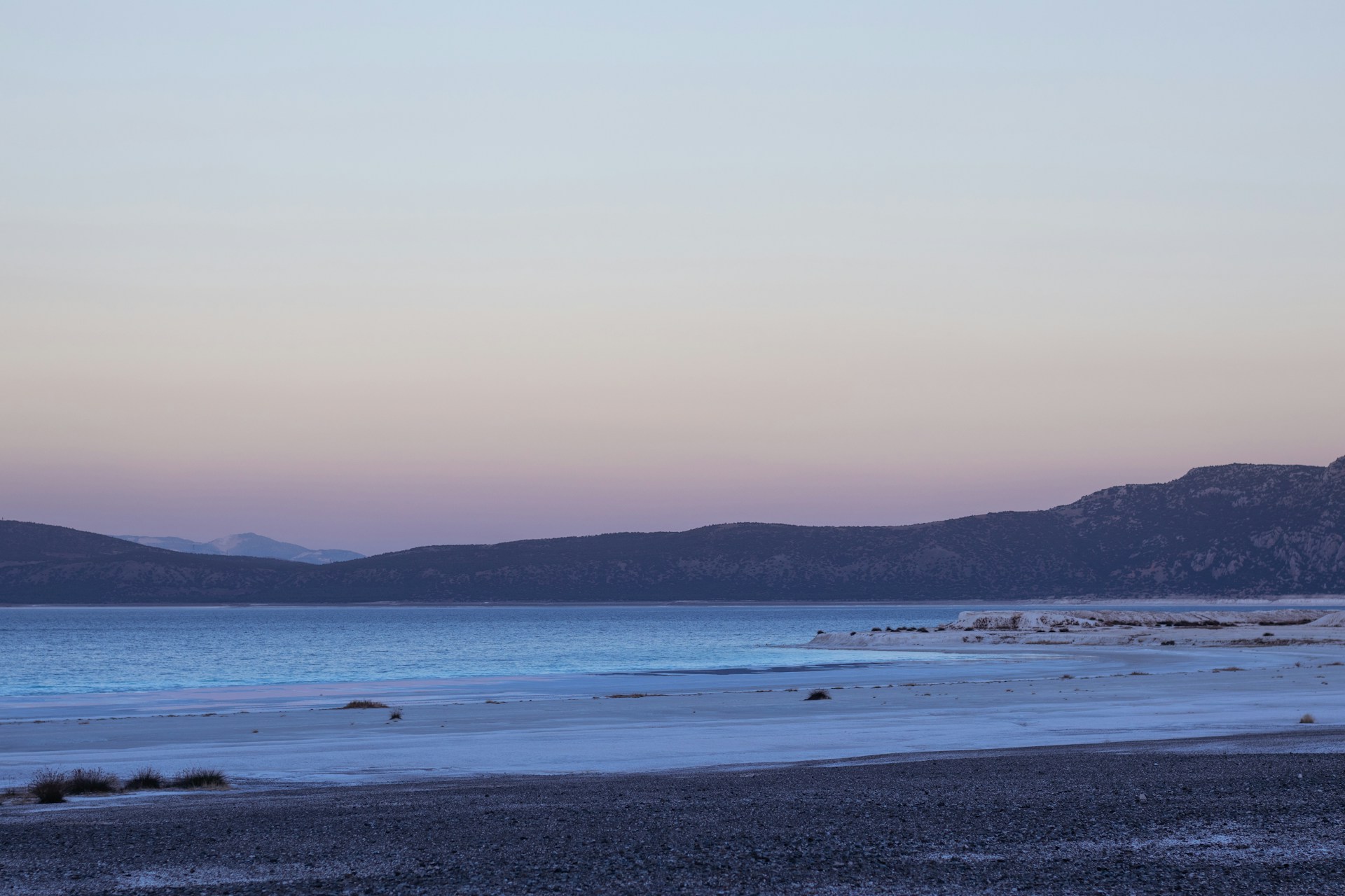 A delicate watercolor painting of a serene lakeside scene at dawn, with soft pastel colors blending gently.