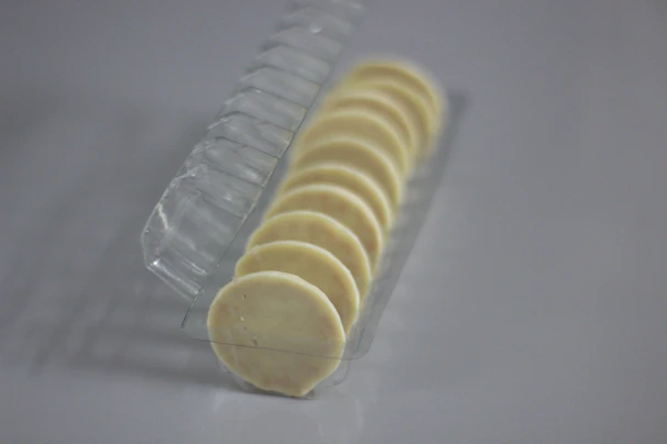 Rows of transparent packaging trays neatly arranged on a clean white factory surface.