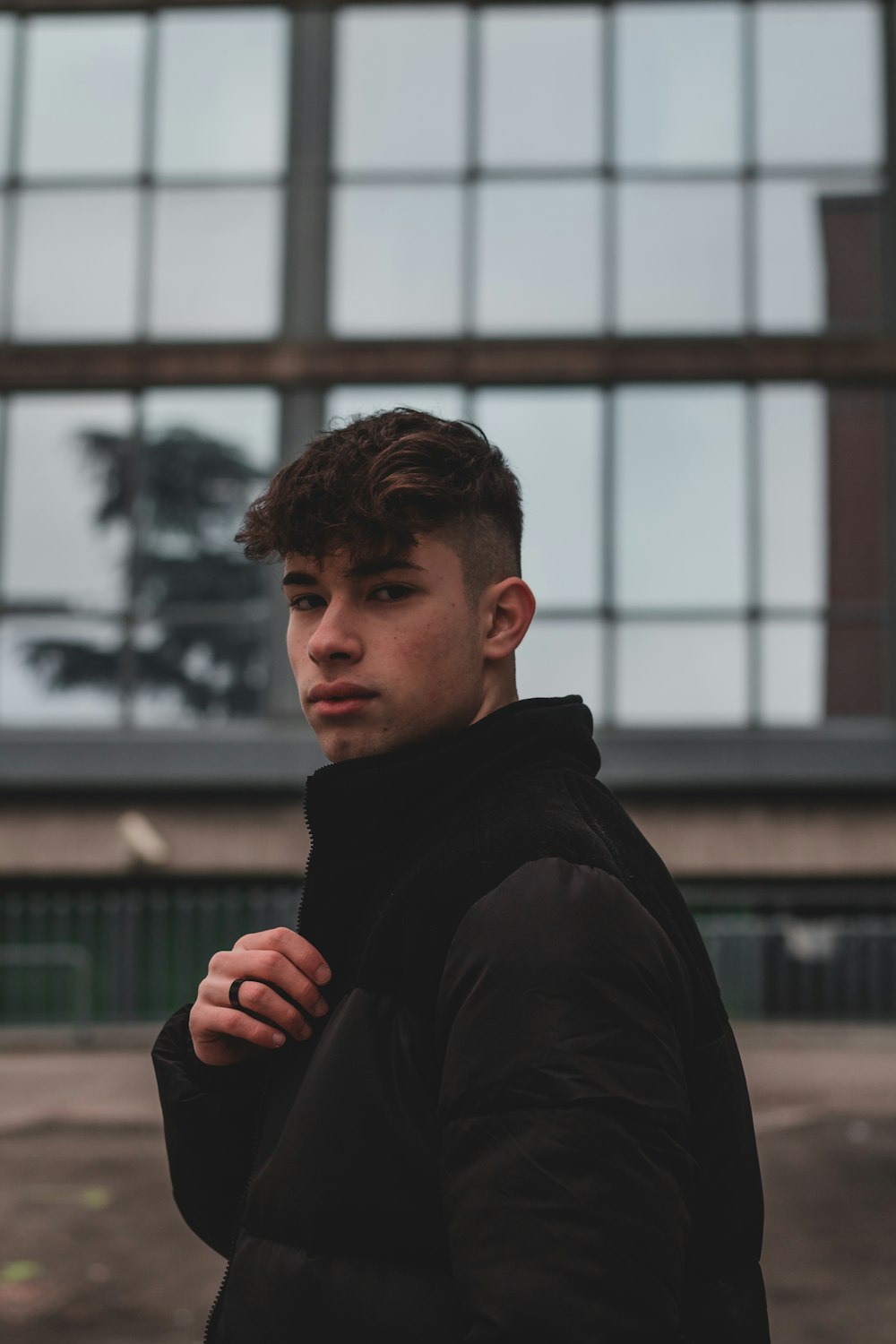 man in black jacket standing near building during daytime