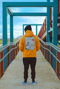 person in pink hoodie and black pants standing on dock during daytime