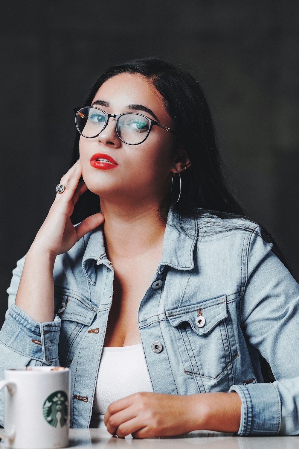 woman in blue denim jacket wearing red framed eyeglasses