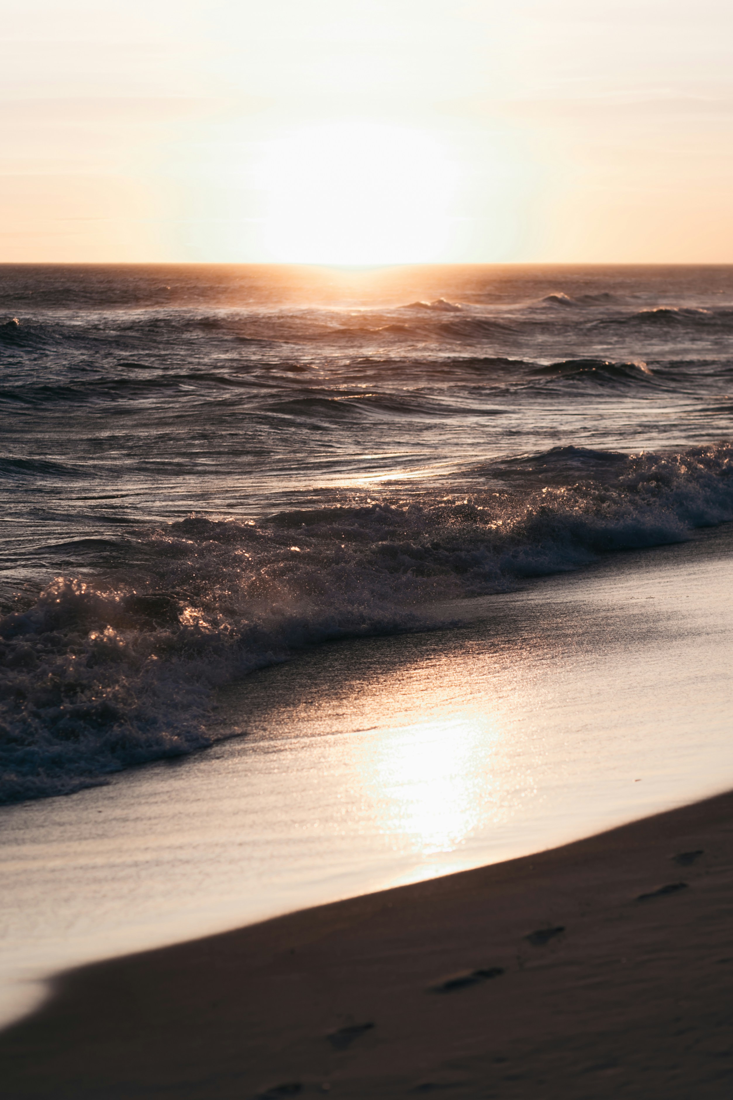 ocean waves crashing on shore during sunset