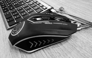 A traditional nylon fabric mouse pad laid flat on a wooden desk beside a sleek mouse.