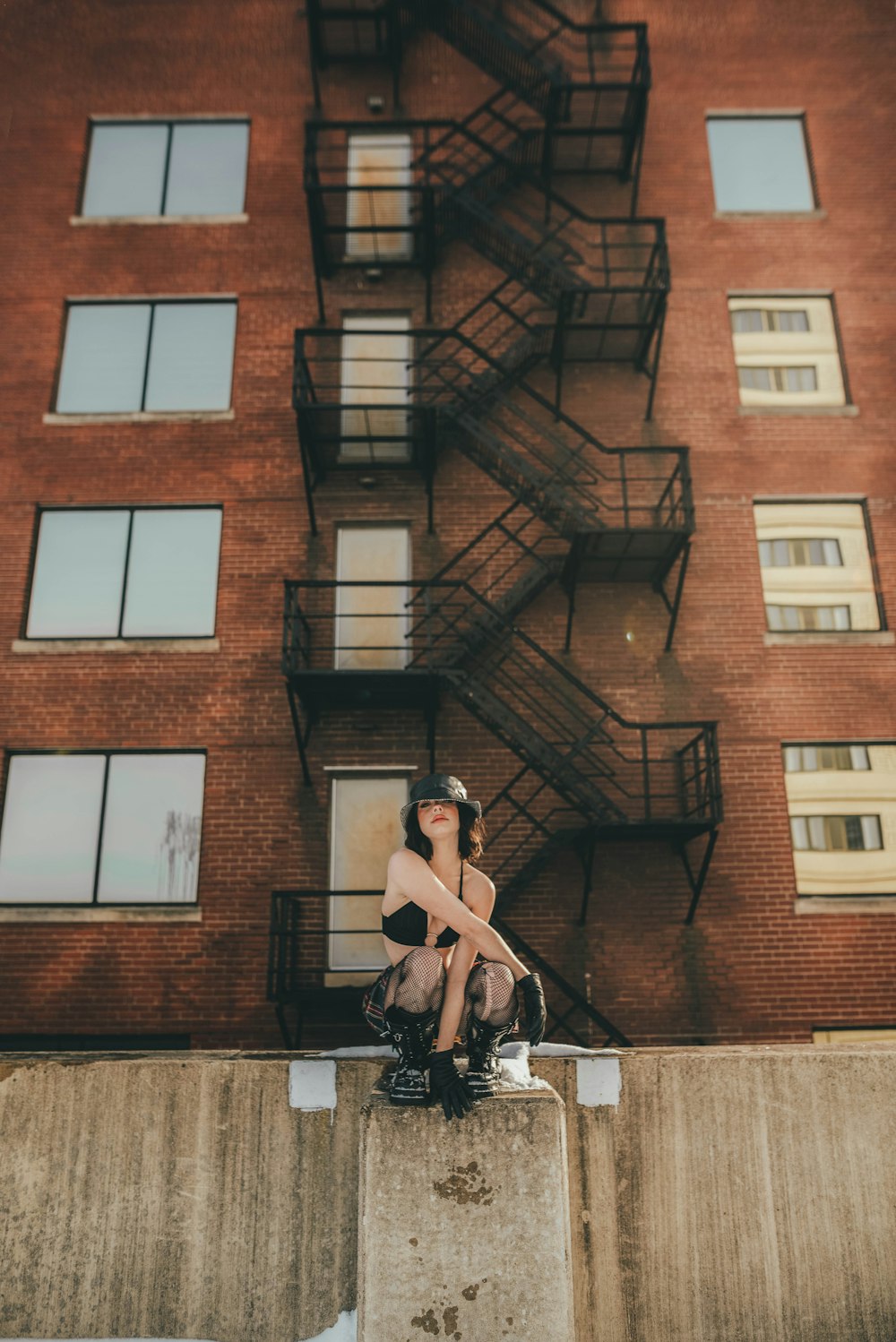 man in black shorts and black tank top standing beside brown concrete building during daytime