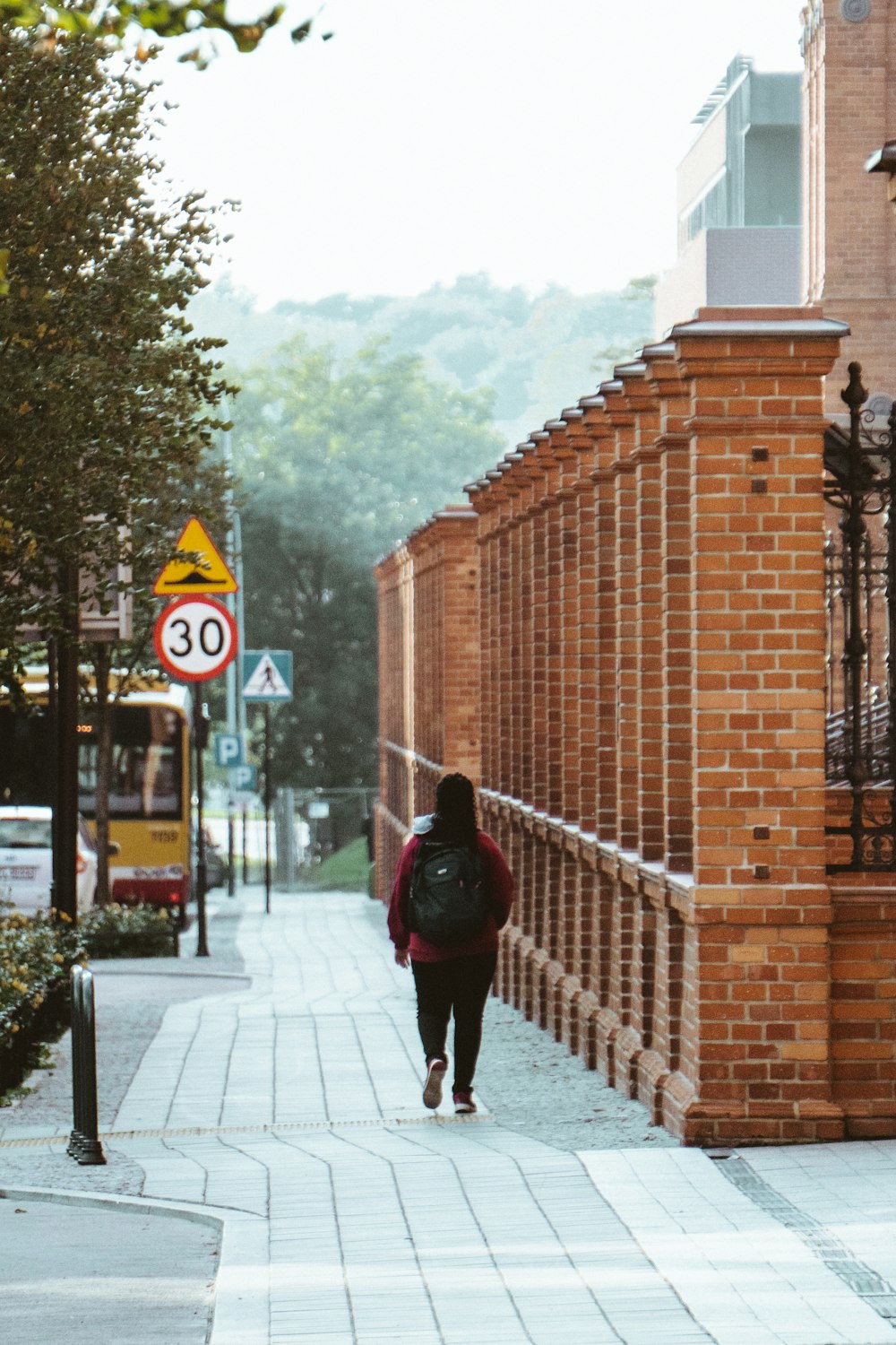 woman in black jacket walking on sidewalk during daytime