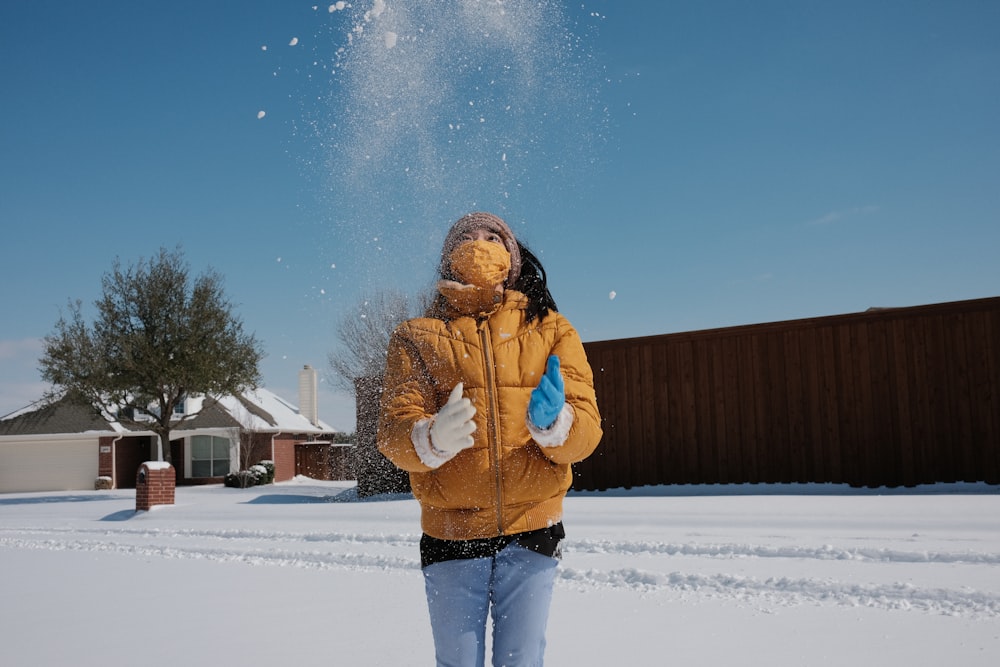woman in brown jacket and blue denim jeans standing on snow covered ground