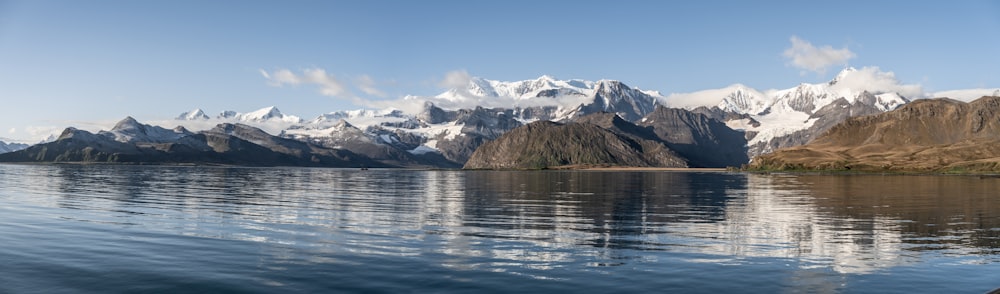 body of water near mountain under blue sky during daytime