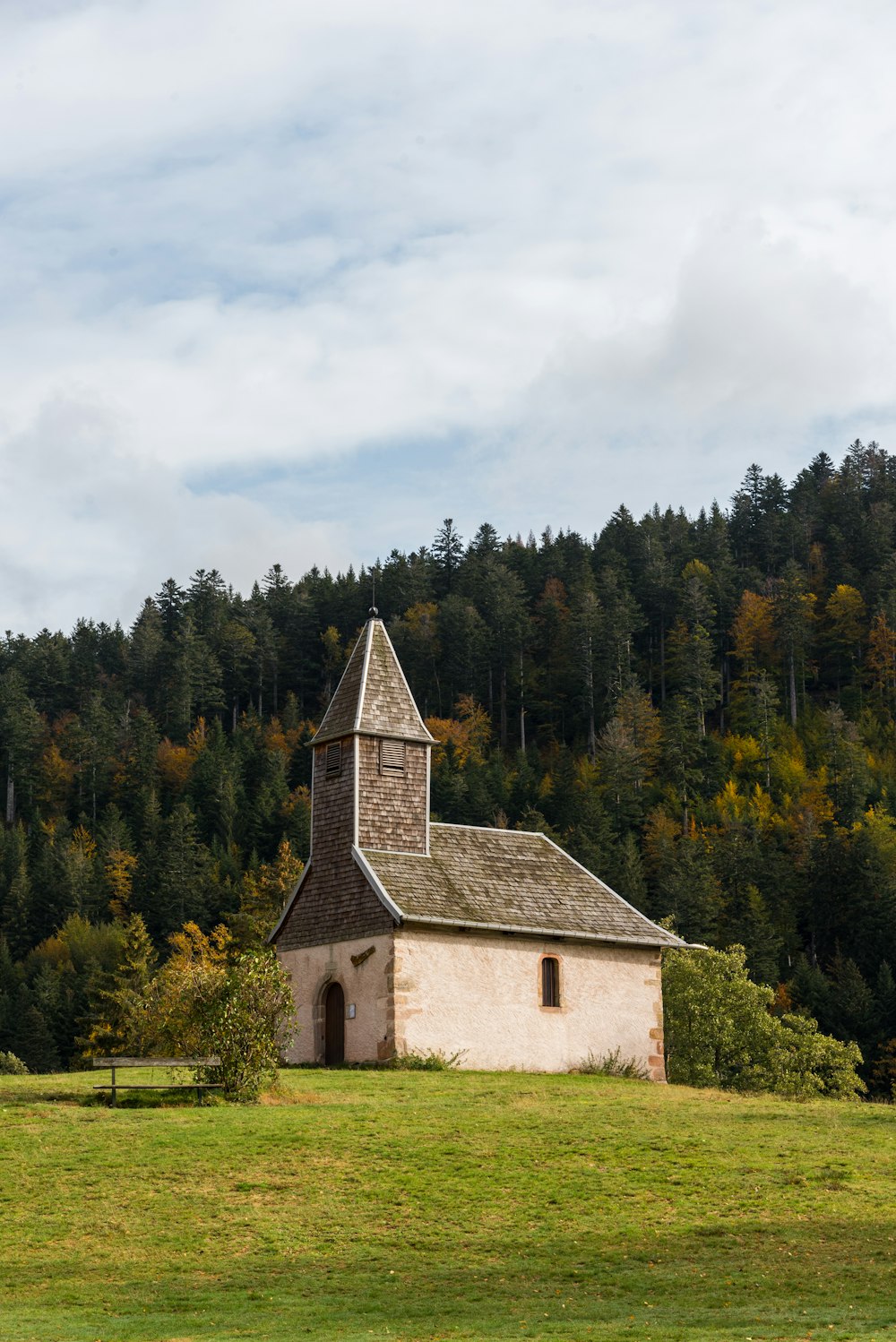 brown and white church surrounded by green trees under white clouds