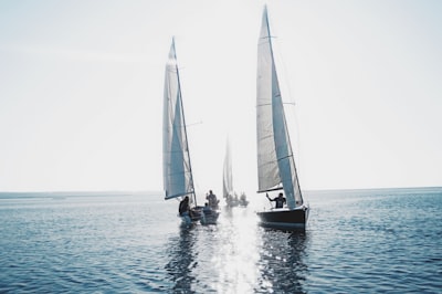 white sail boat on sea during daytime sail teams background