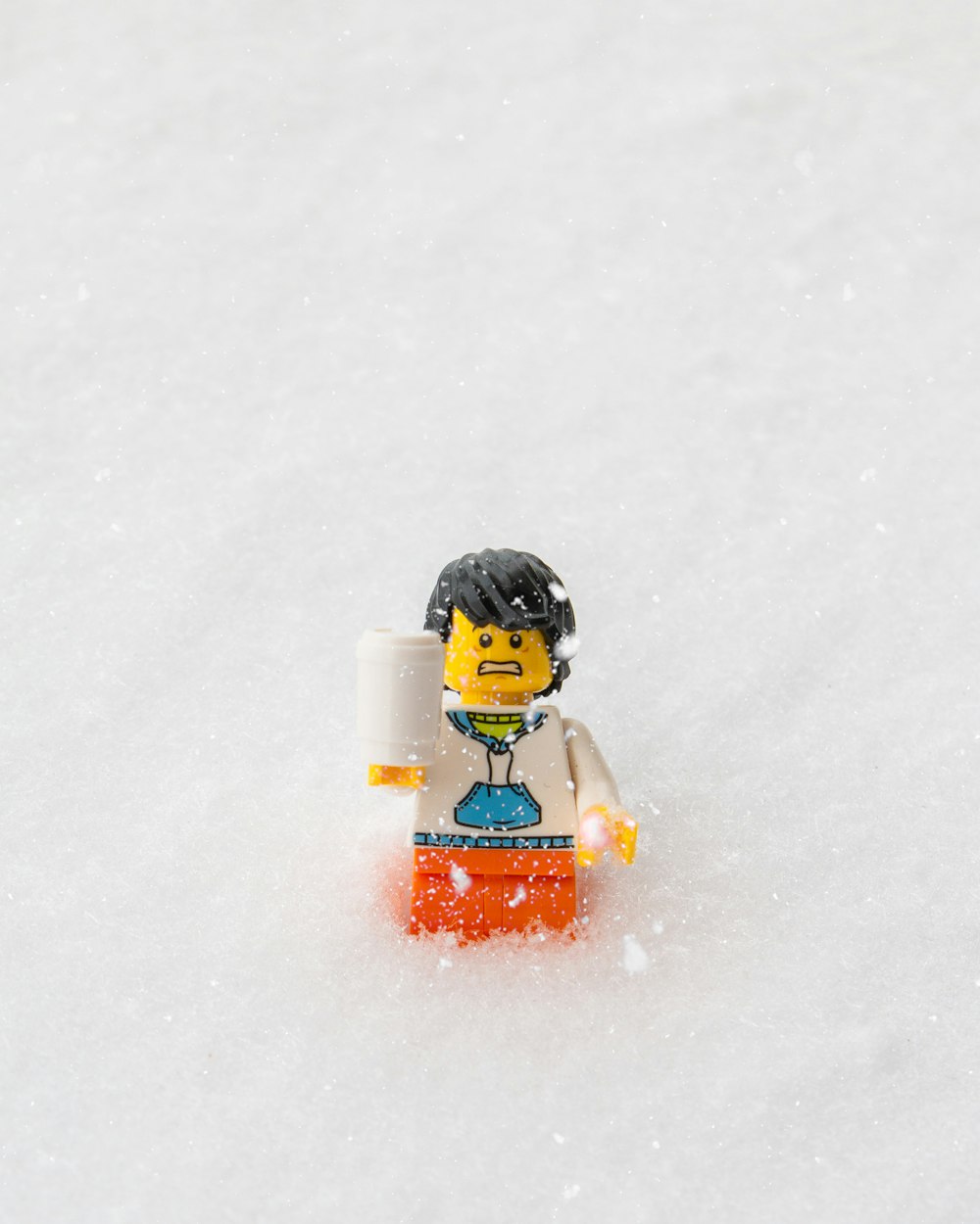 girl in orange jacket and black pants sitting on snow covered ground during daytime