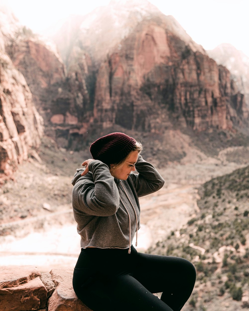 woman in black long sleeve shirt and black pants sitting on rock formation during daytime