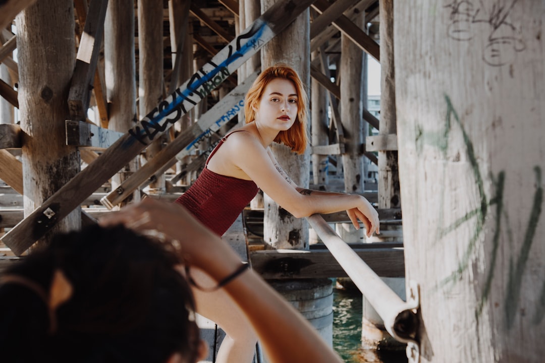 woman in red tube dress standing on bridge during daytime