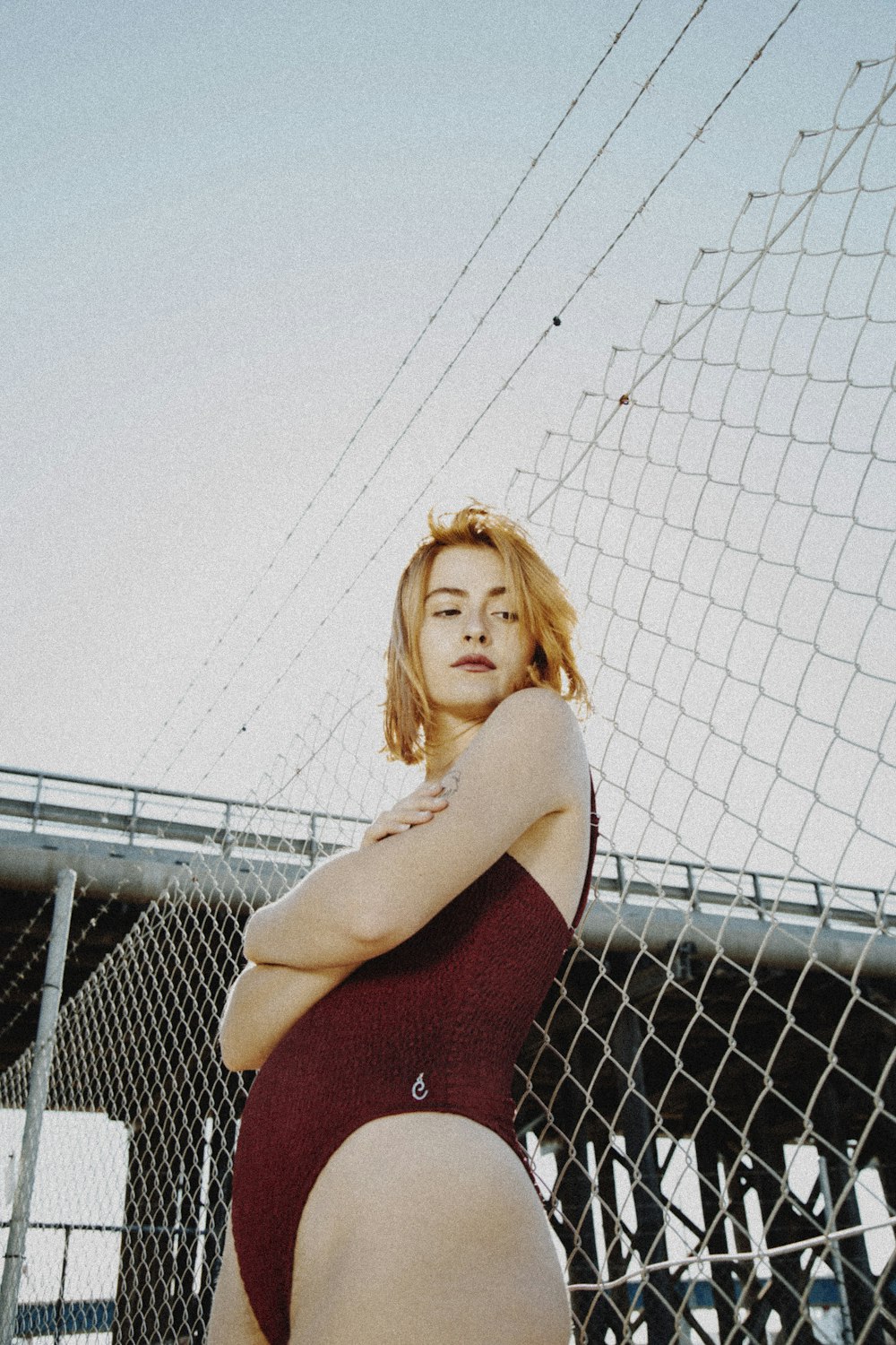 woman in red tank top leaning on chain link fence