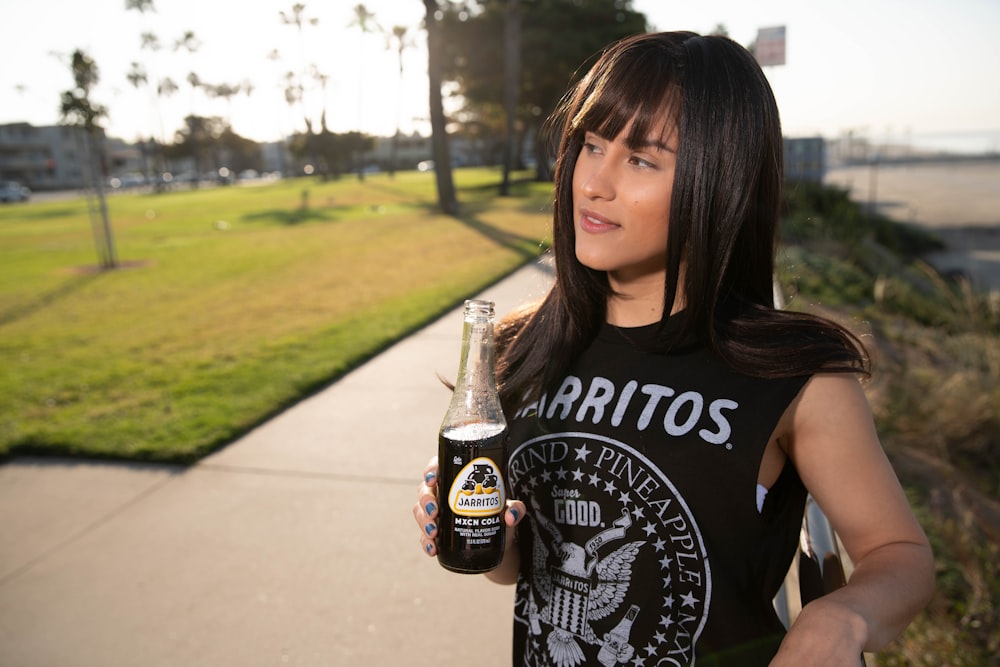 woman in black and white crew neck t-shirt holding coca cola bottle