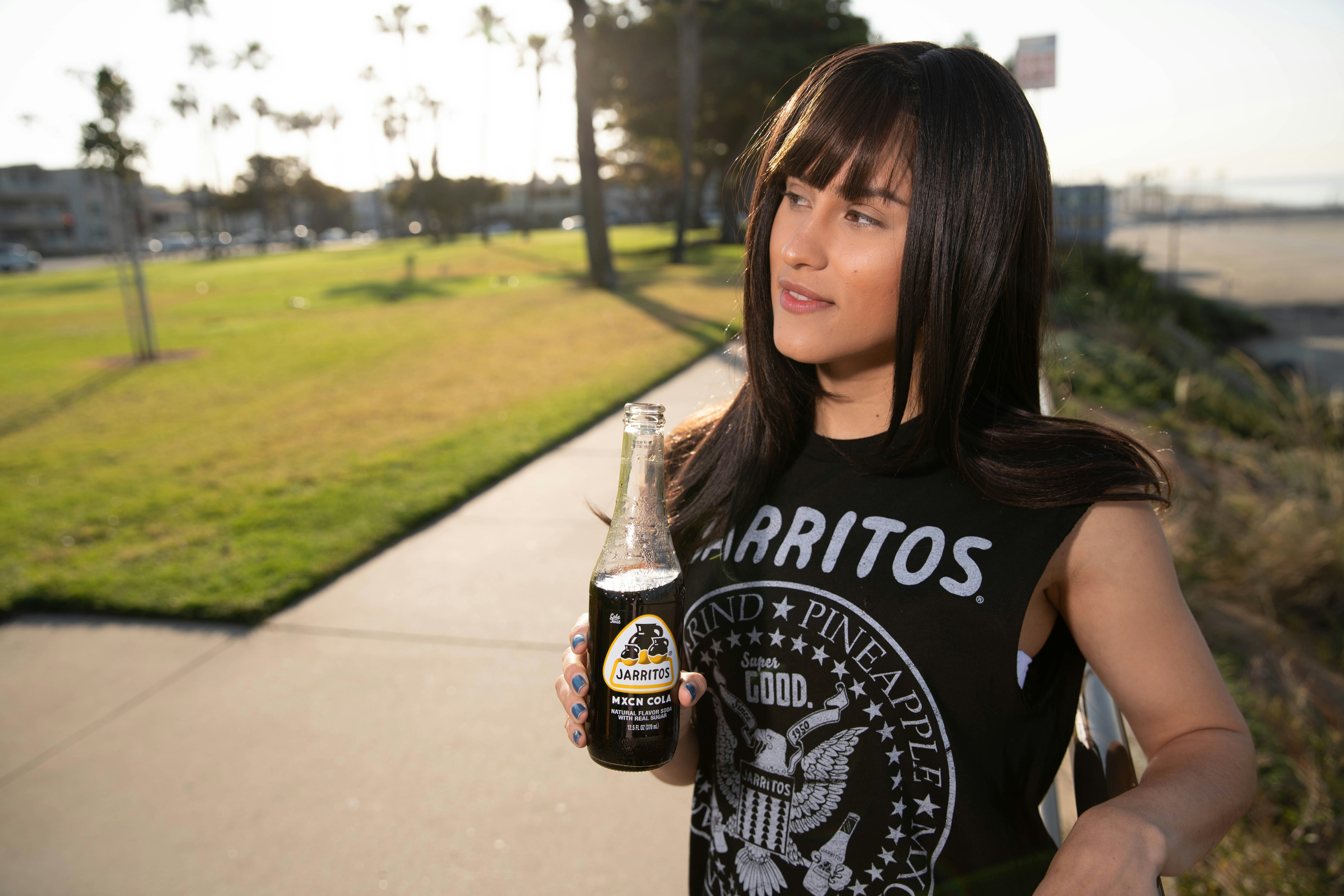 Woman drinks a Jarritos Soda at the boardwalk in Long Beach, California.