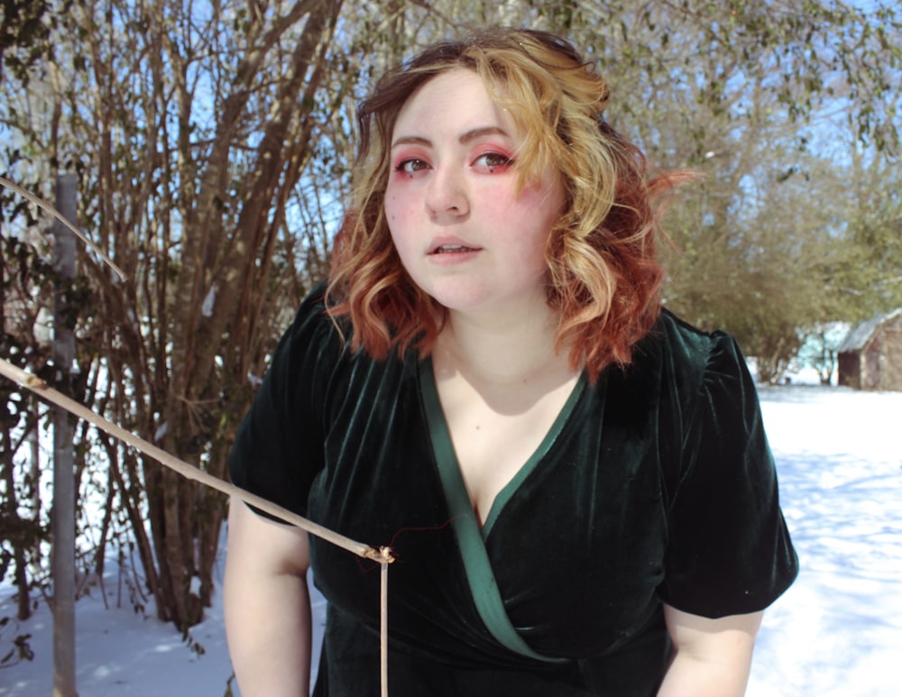 woman in black and green zip up jacket standing near bare trees during daytime