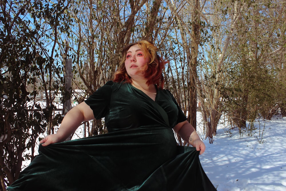 woman in black dress standing near bare trees during daytime