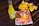 A vibrant scene with a bottle of Jarritos pineapple soda next to a plate of spicy snacks covered in melted cheese and spices, garnished with a lime wedge. In the background, a bowl filled with tortilla chips is visible, all placed on a rustic wooden table.