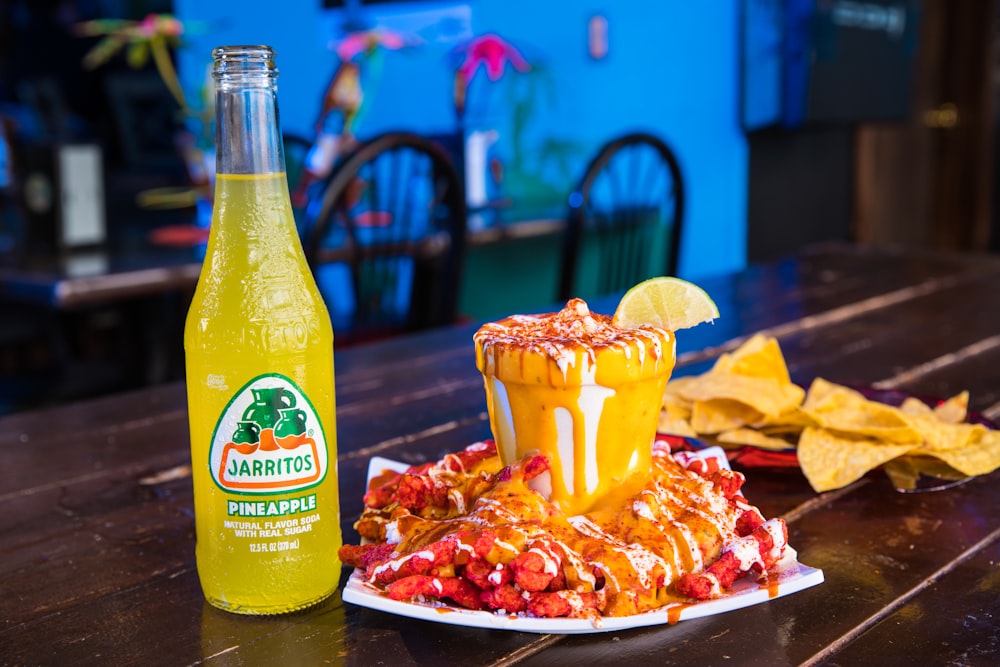 yellow and green labeled bottle beside red and white ceramic bowl with food