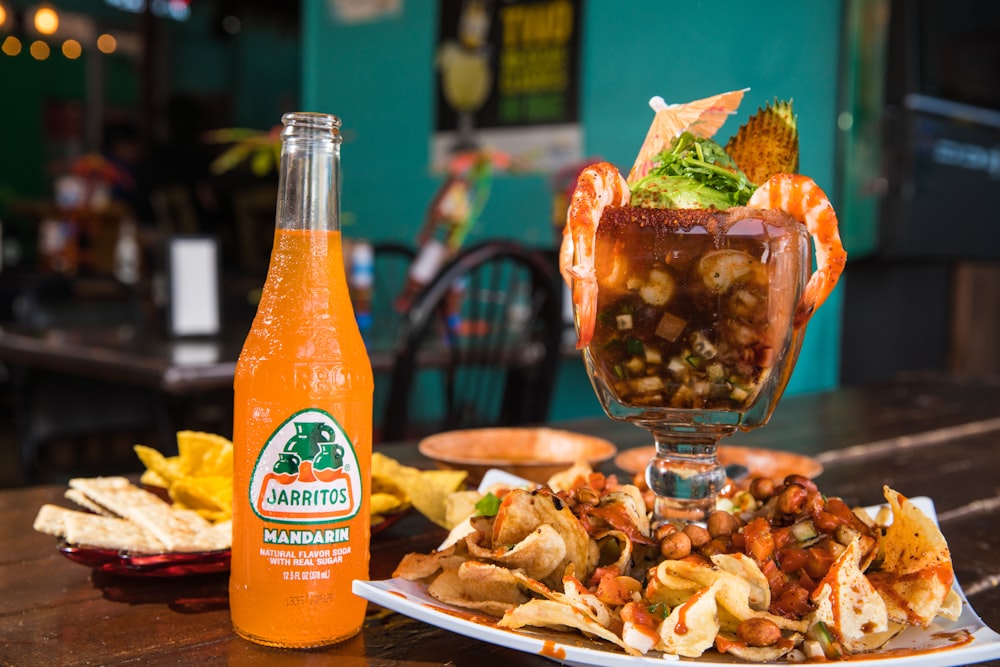 a plate of food and a bottle of orange juice on a table