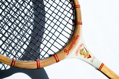 A vintage wooden tennis racket resting on a net, evoking the sport’s rich history.